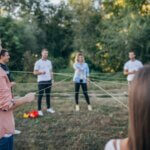 Junge Erwachsene stehen im Kreis und halten eine Schnur, die ein Netz zwischen den Personen bildet.