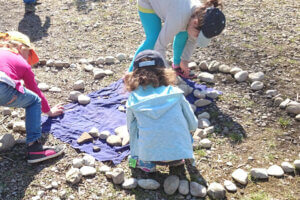 Kinder legen Steinen zu einer langen Schlange.