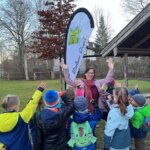 Simone Gerhardt winkt. Vor ihr stehen winkende Kinder mit dem Rücken zum Betrachter.