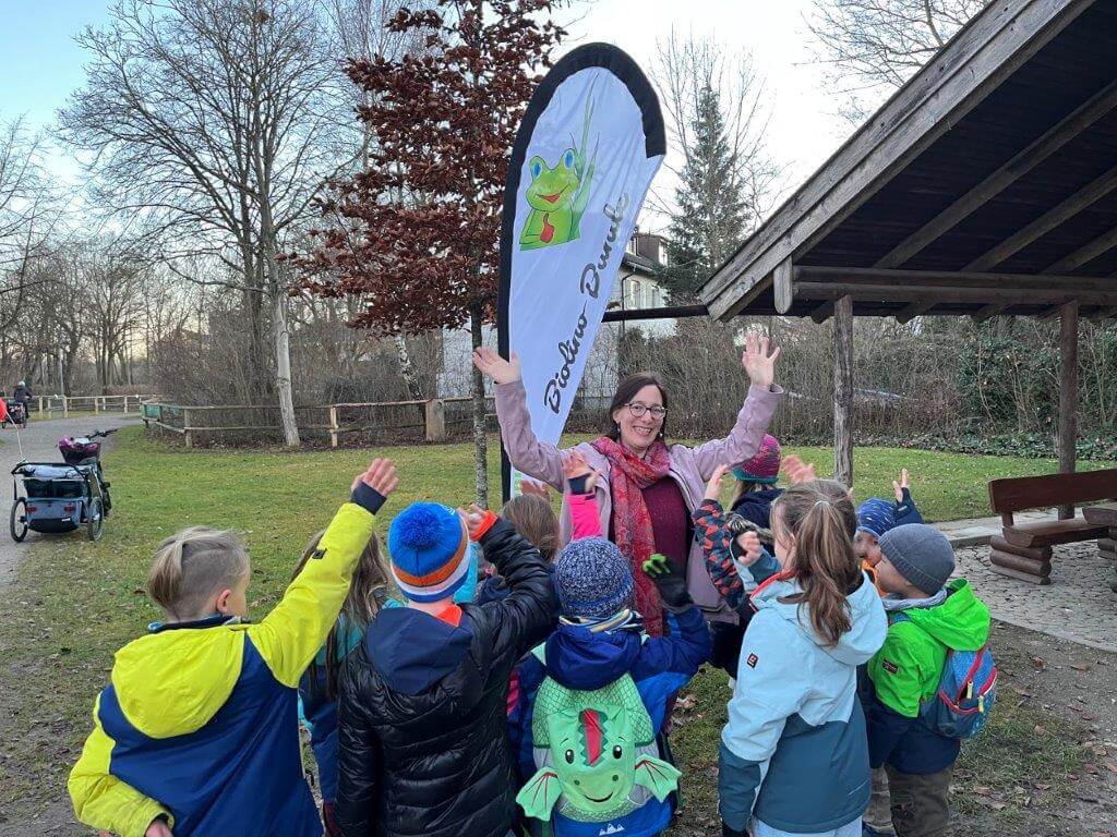 Simone Gerhardt winkt. Vor ihr stehen winkende Kinder mit dem Rücken zum Betrachter.
