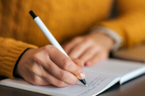 eine Person schreibt in ein Buch