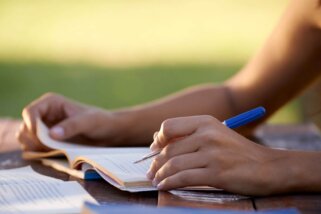 Lektorat Nahaufnahme, Hände einer Frau, die einen Stift und ein Manuskript halten.