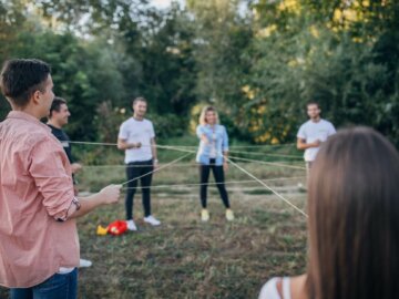 Ökonetz Junge Erwachsene stehen im Kreis und halten eine Schnur, die ein Netz zwischen den Personen bildet.