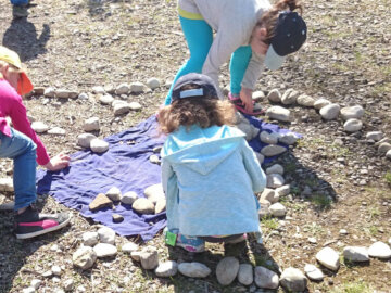 Kinder legen Steinen zu einer langen Schlange.